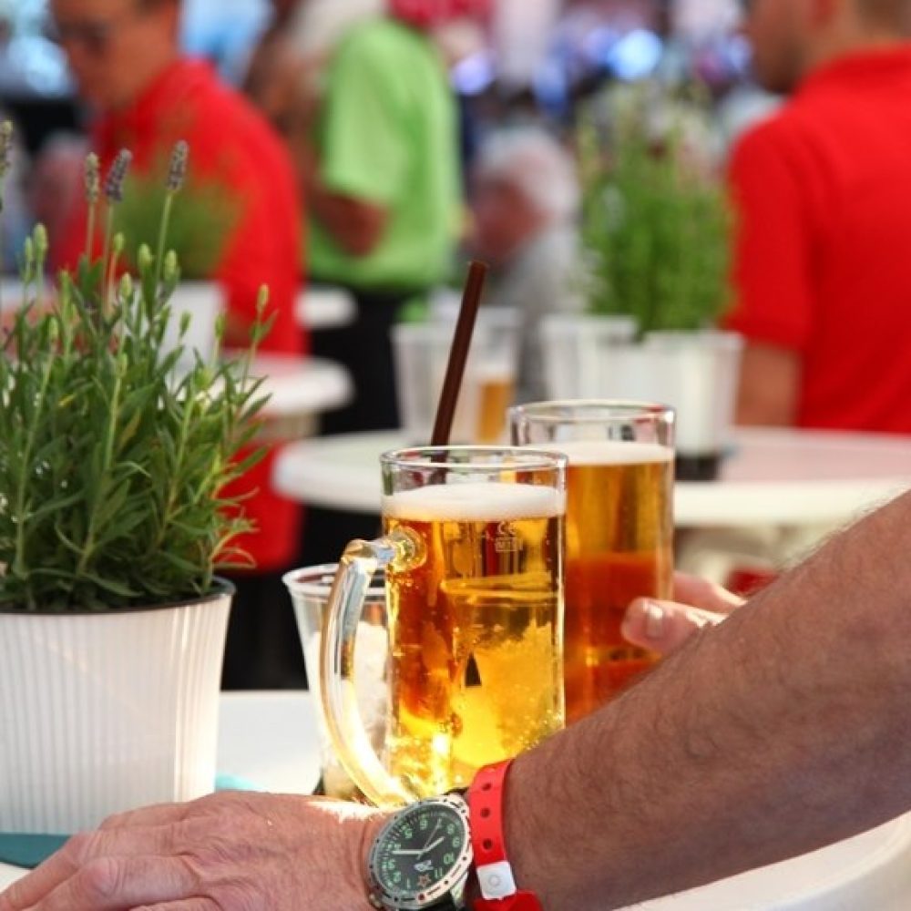 Frisch gezapftes Bier auf einem Tisch im Festzelt, Besucher im Hintergrund.