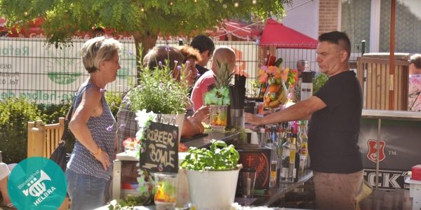 Besucher stehen an einer dekorierten Cocktailbar im Außenbereich des Fests.