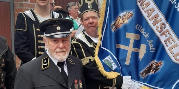 Traditionell gekleidete Männer mit Uniform und Bergmannsbanner ‚Mansfeld – Glück Auf‘ beim Umzug.