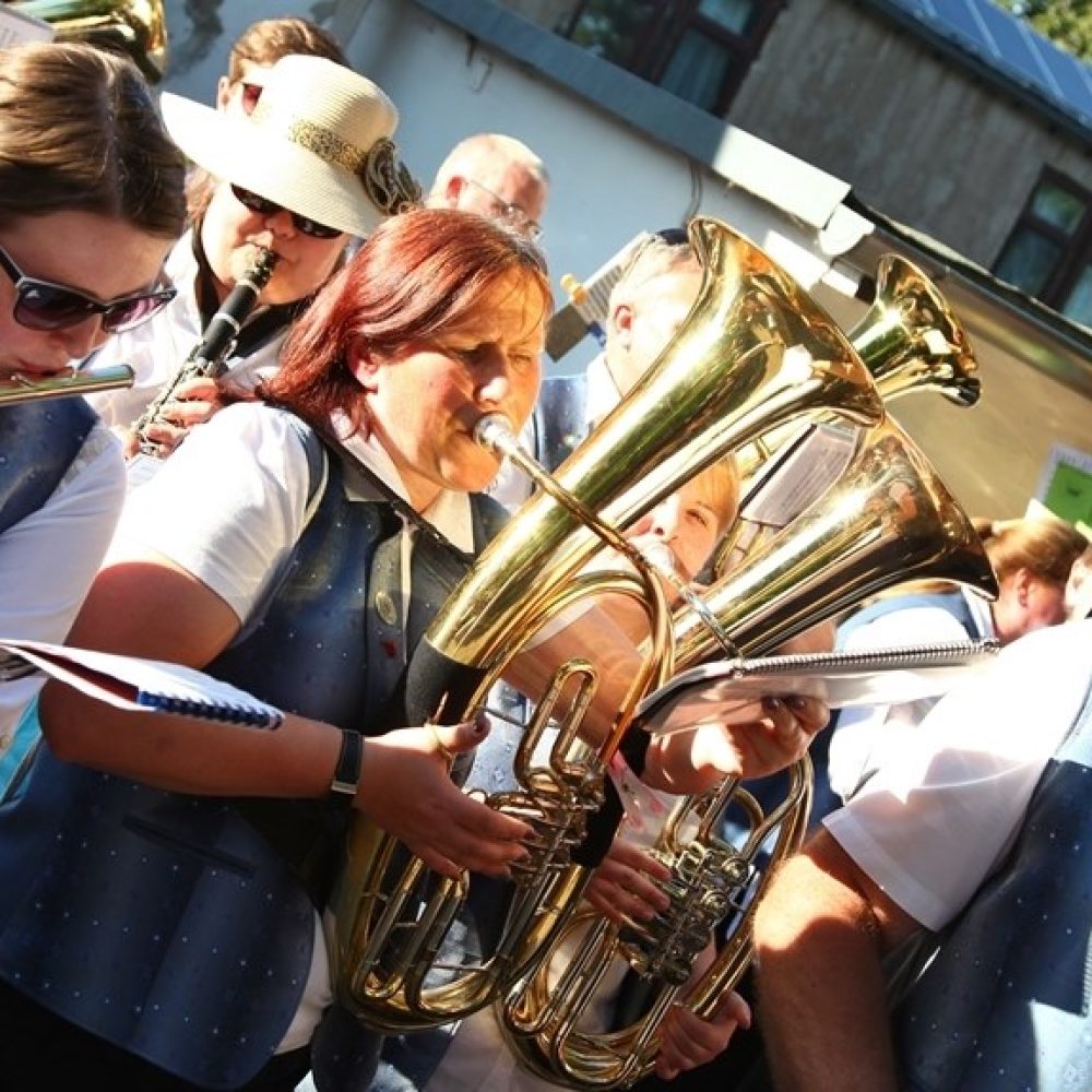 Blasmusikerin in Tracht spielt Tuba in einer Musikgruppe beim Festumzug.