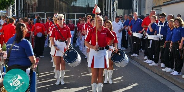 Trommlerinnen in rot-weißen Uniformen marschieren in Formation beim Festumzug.