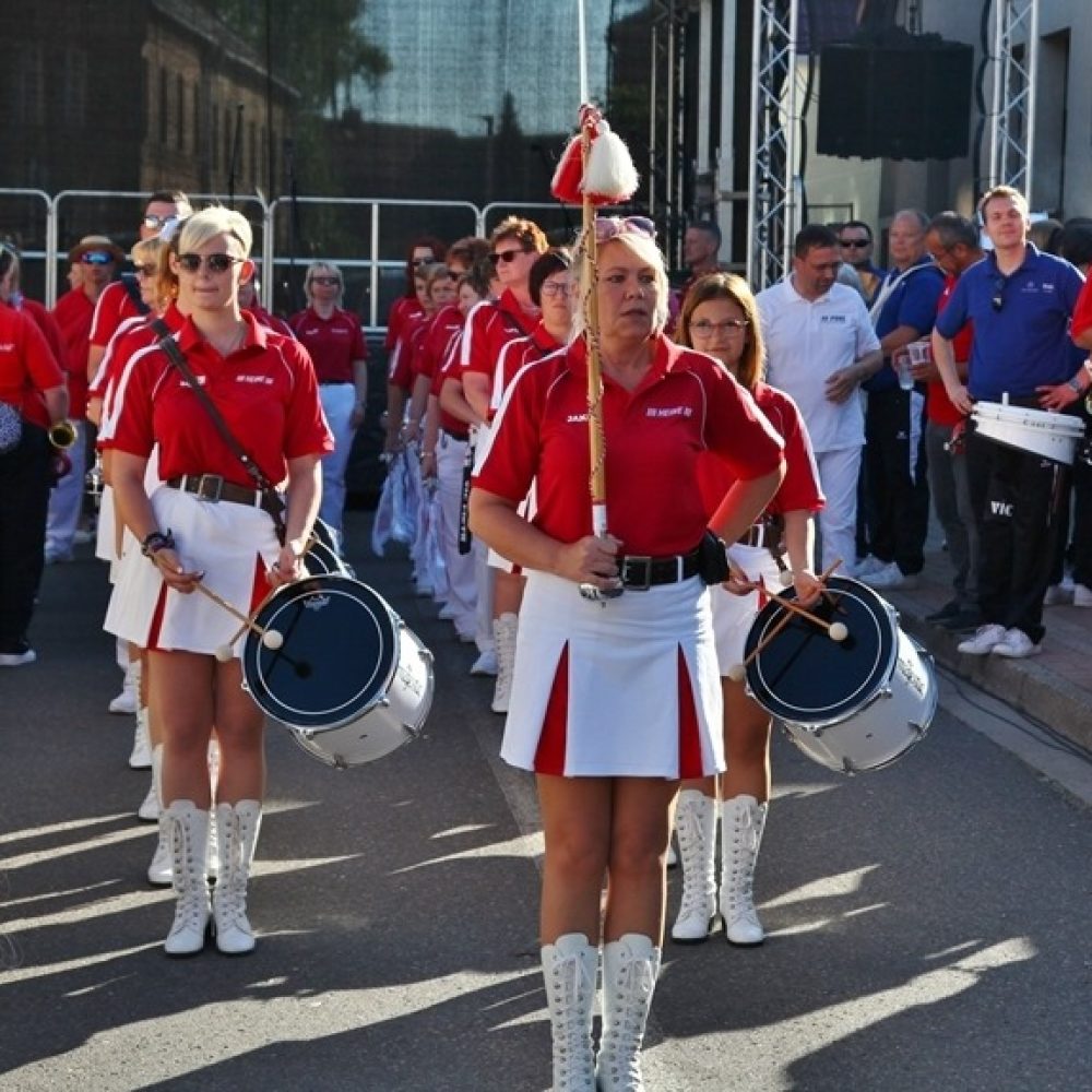 Trommlerinnen in rot-weißen Uniformen marschieren in Formation beim Festumzug.