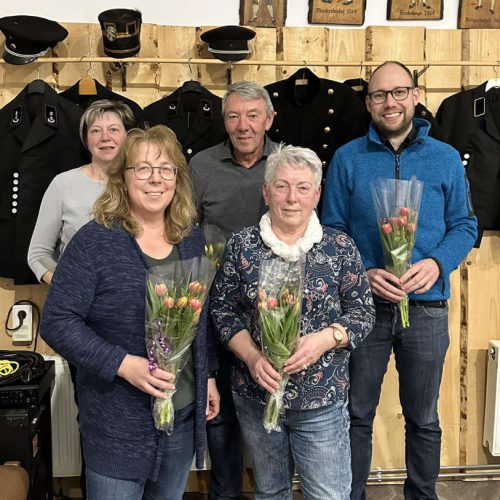 Teamfoto Blasmusikfest Mansfelder Land e.V. Fünf Vereinsmitglieder des Blasmusikfest Mansfelder Land e.V. posieren lächelnd mit Blumensträußen, im Hintergrund traditionelle Bergmannsuniformen.